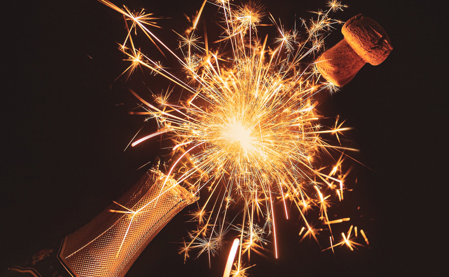 Fireworks exploding from a popped champagne bottle.