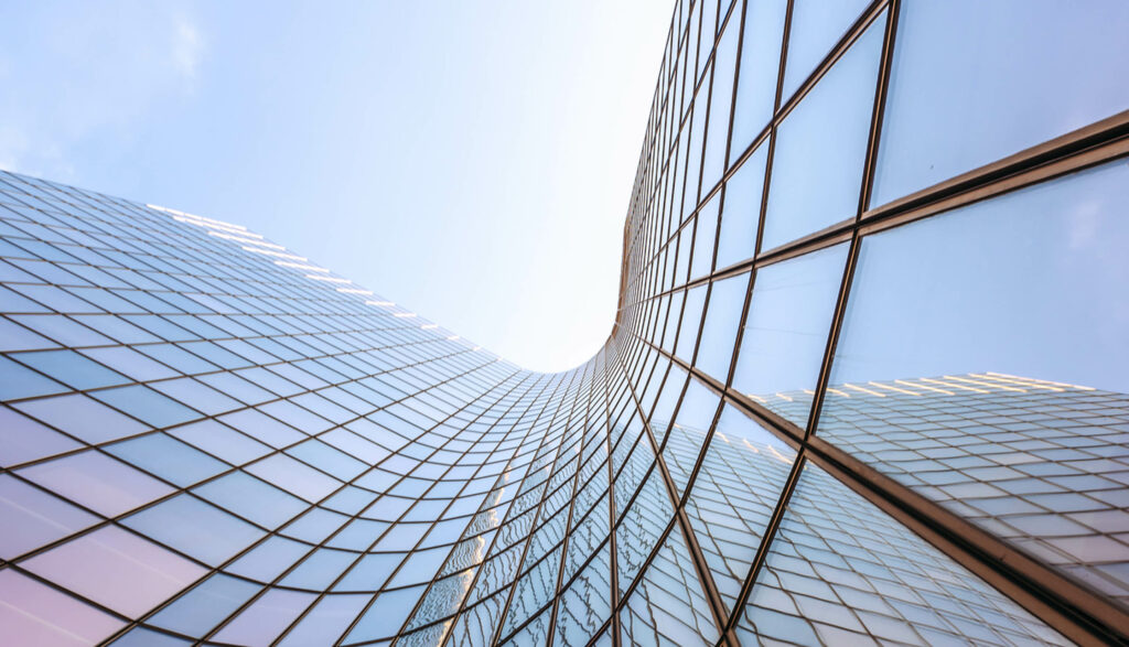 Modern curved building reflecting blue sky in the windows.